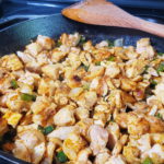 View of cut chicken added to onions and peppers