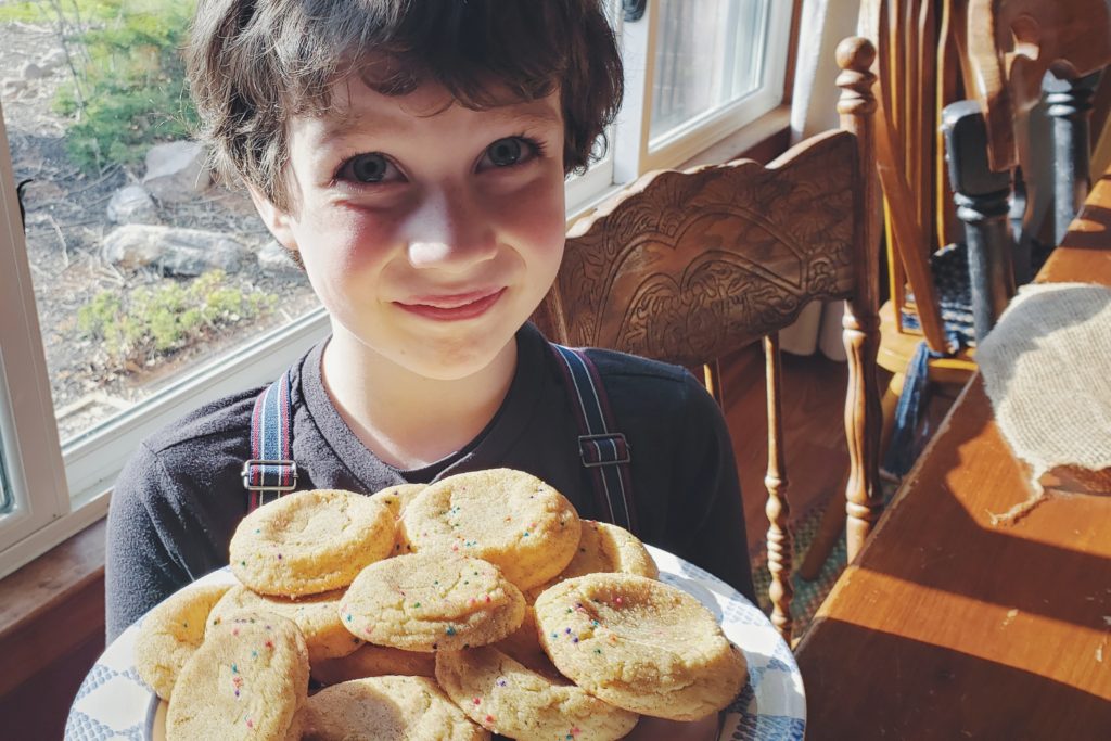 Picture of grandson holding a plate of cookies he helped bake.